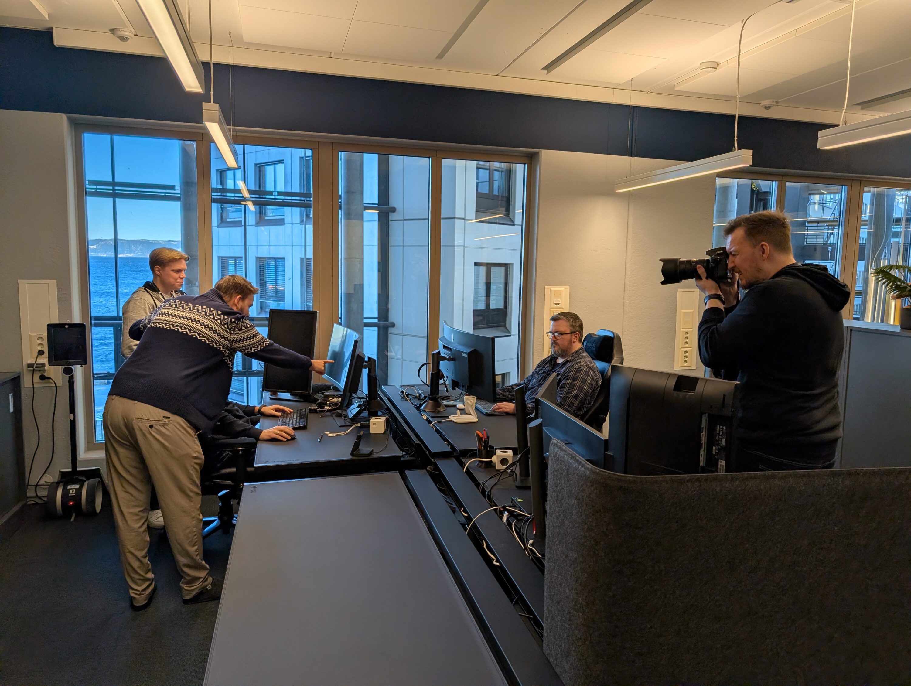 Bilde av fotograf som tar bilde av mennesker ved datamaskin