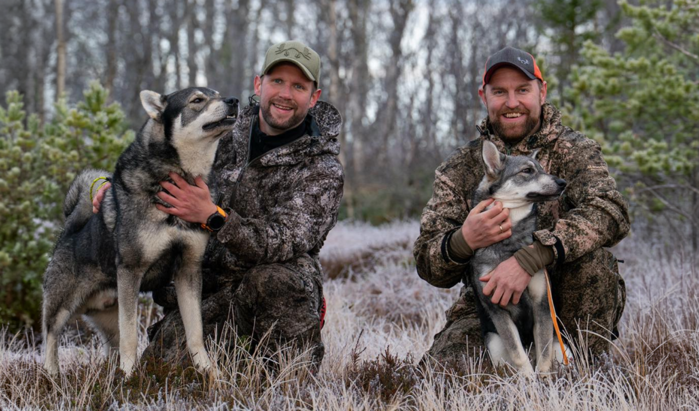 2 men med vær sin hund i skogen.